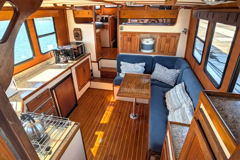 Slide: The Image of Interior of a 1997 Nordic Tug 32, featuring cozy seating and a compact kitchen area. - 16