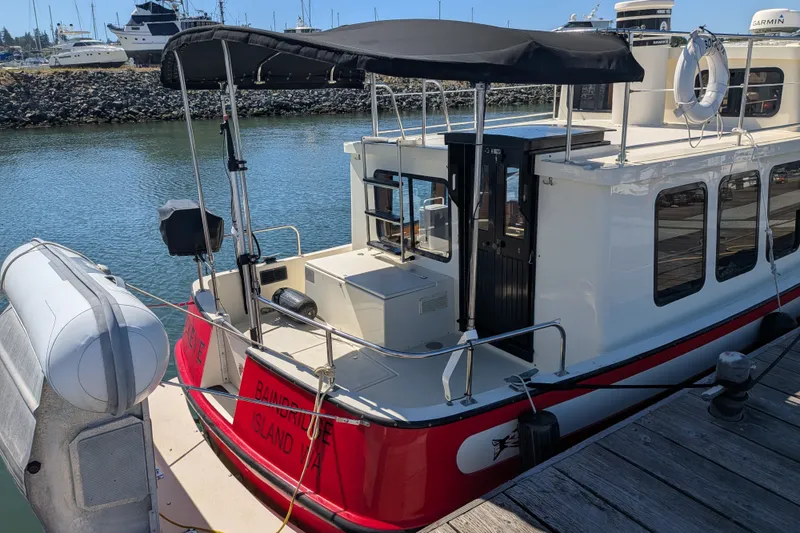 Slide: The Image of 1997 Nordic Tug 32 docked at marina, featuring red and white exterior with canopy. - 9