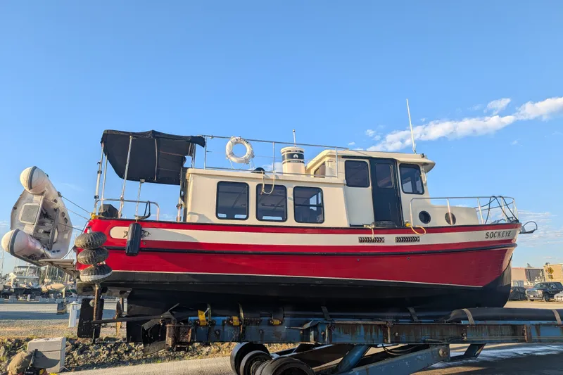 Slide: The Image of Red and white 1997 Nordic Tug 32 boat on a trailer under a clear blue sky. - 48