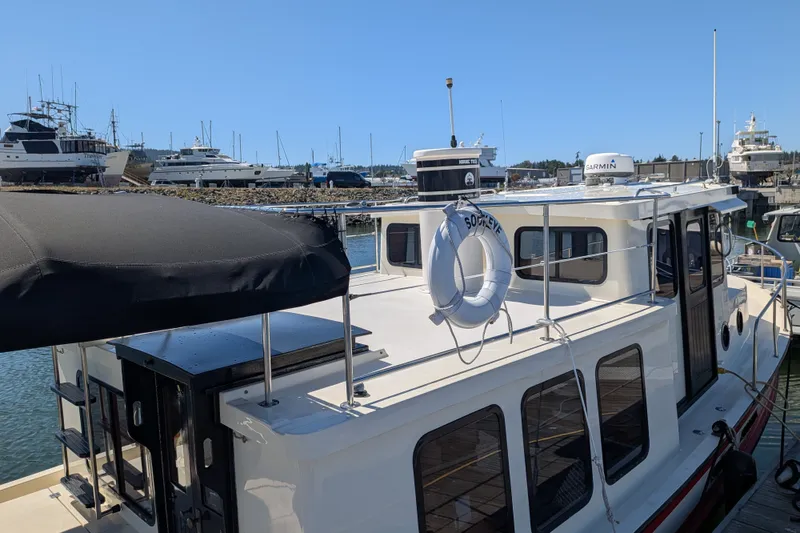 Slide: The Image of 1997 Nordic Tug 32 docked at marina, featuring a lifebuoy and Garmin equipment. - 10