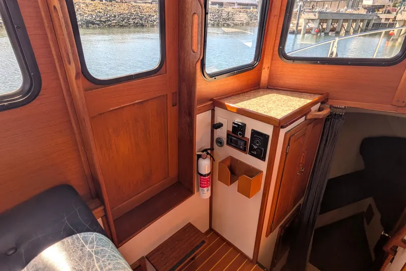 Slide: The Image of Interior of a 1997 Nordic Tug 32 boat, featuring wooden paneling and a control panel. - 36