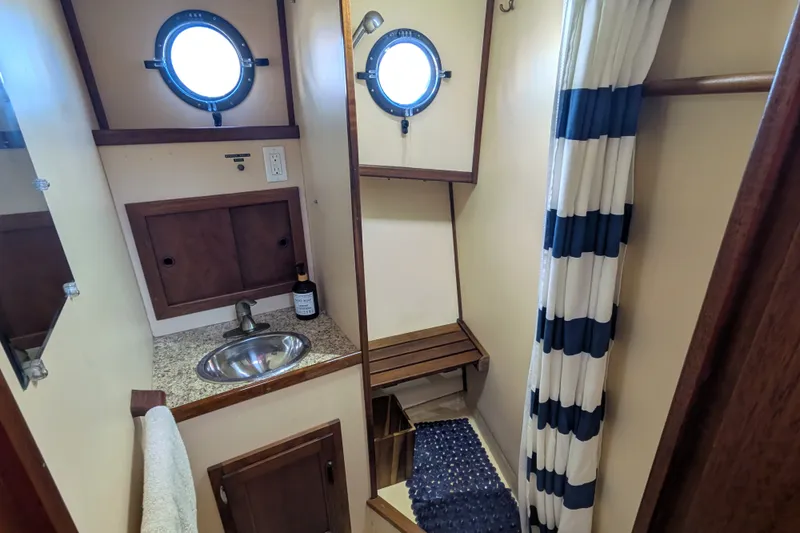 Slide: The Image of 1997 Nordic Tug 32 bathroom with porthole, sink, and striped shower curtain. - 41