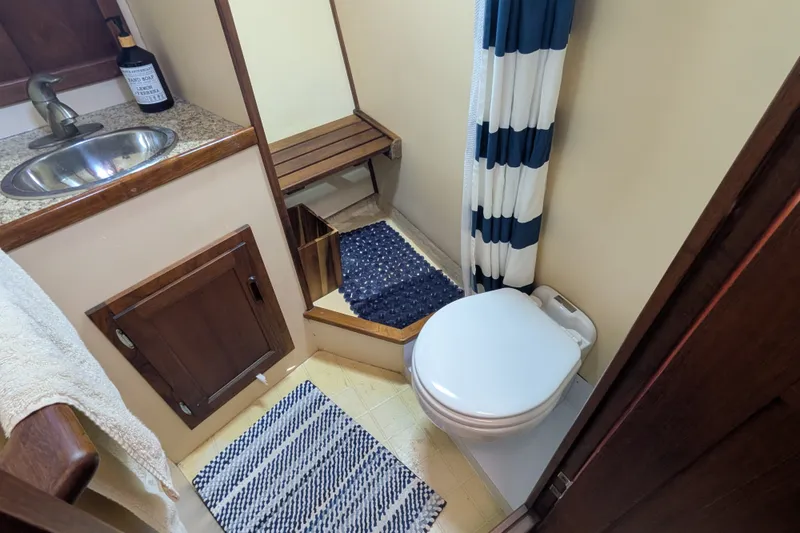 Slide: The Image of Bathroom interior of a 1997 Nordic Tug 32, featuring a sink, toilet, and striped shower curtain. - 42