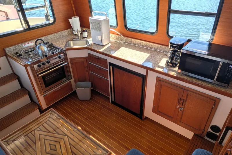 Slide: The Image of Cozy 1997 Nordic Tug 32 galley with stove, sink, and appliances, overlooking water. - 22