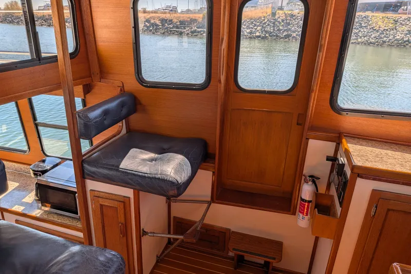 Slide: The Image of Interior of a 1997 Nordic Tug 32, featuring wooden paneling and a cushioned seat. - 38