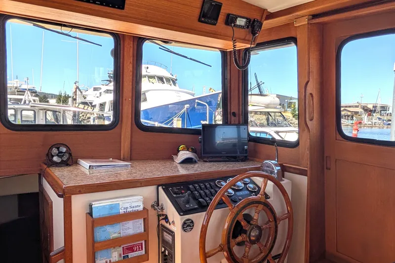 Slide: The Image of Interior of a 1997 Nordic Tug 32 boat with wooden helm and marina view. - 30
