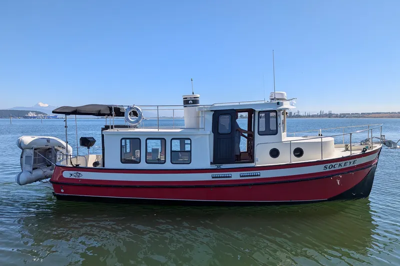 Slide: The Image of 1997 Nordic Tug 32 boat on calm water, featuring a red and white design. - 3