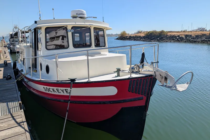 Slide: The Image of 1997 Nordic Tug 32 docked, featuring red and white design, with clear blue water background. - 6