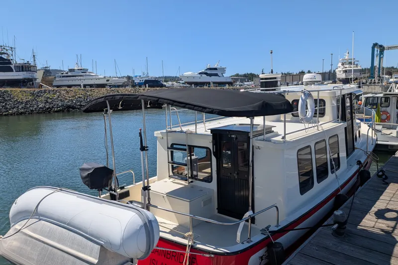 Slide: The Image of 1997 Nordic Tug 32 docked at marina with inflatable boat and canopy. - 11
