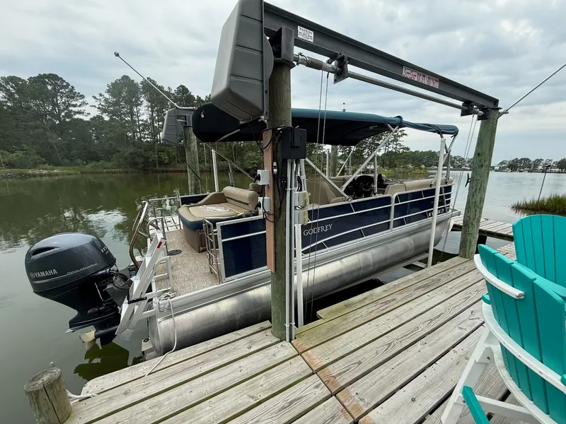 Slide: The Image of A 2022 Godfrey Sweetwater 2286 SFL pontoon boat docked at a wooden pier in calm waters. - 3