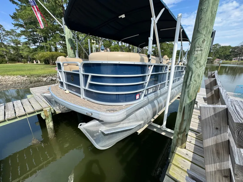The Image of A 2022 Godfrey Sweetwater 2286 SFL pontoon boat docked at a wooden pier in calm waters. - 0