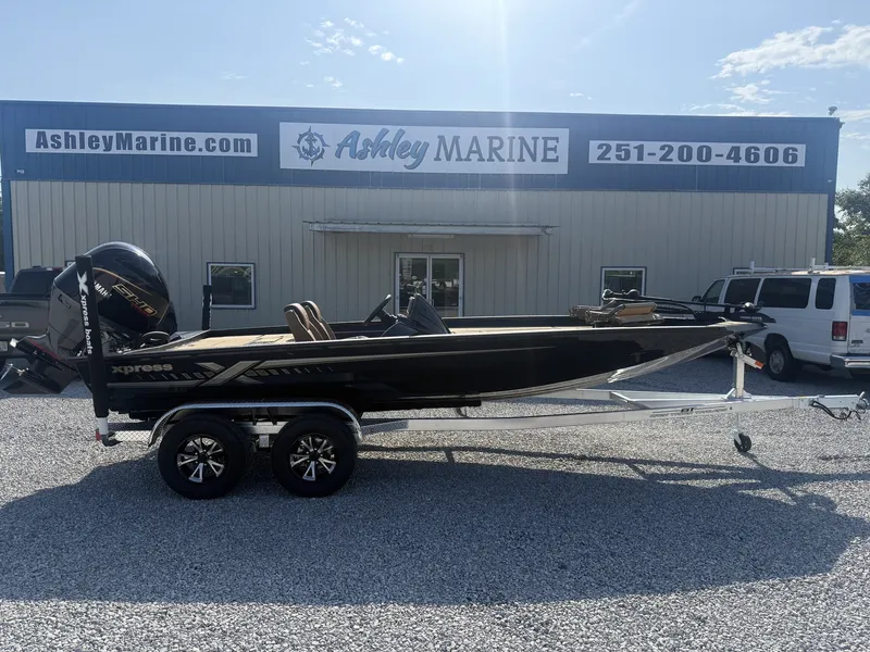 The Image of A 2027 Xpress H20 Crappie boat on a trailer in front of a building with "Ashley Marine" signage. - 1