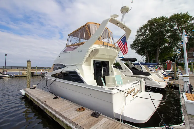 Slide: The Image of A 2006 Carver 33 Super Sport yacht docked. It features an elevated helm and an American flag. - 17