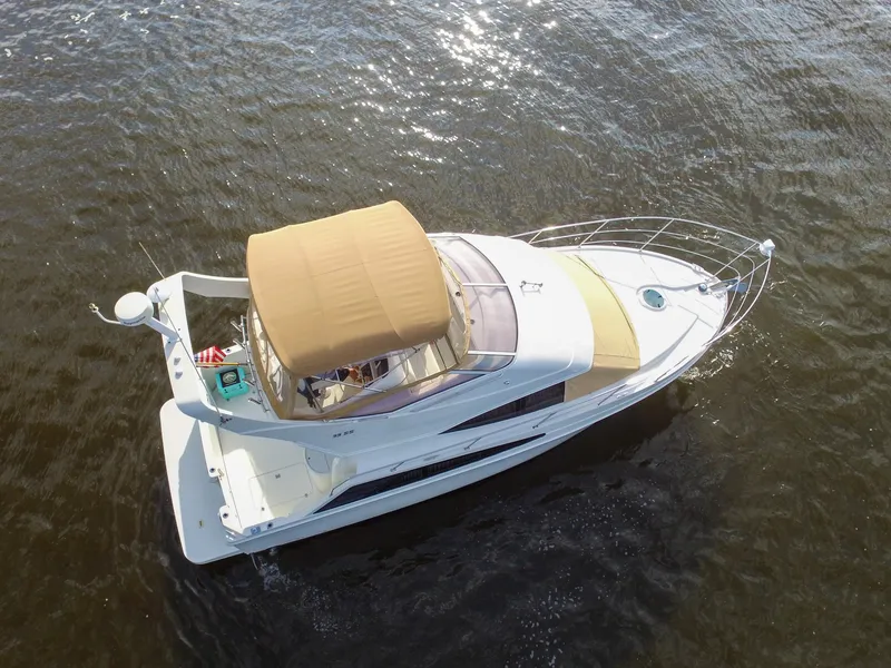 Slide: The Image of A 2006 Carver 33 Super Sport on calm water with a beige canopy. - 14
