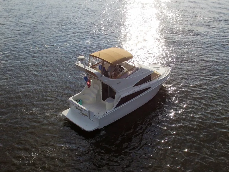 Slide: The Image of The 2006 Carver 33 Super Sport cruises on calm water with sunlight glistening on the deck. - 13