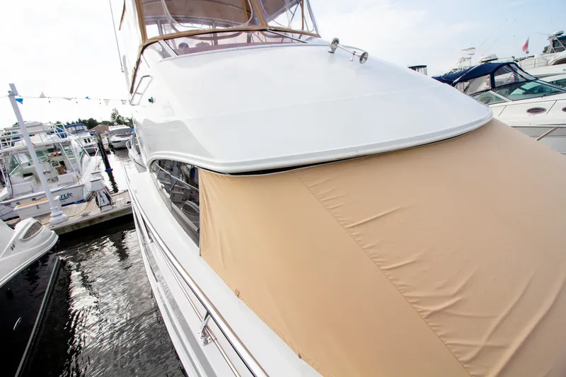 Slide: The Image of The 2006 Carver 33 Super Sport is docked, featuring a beige cover over the bow. - 39