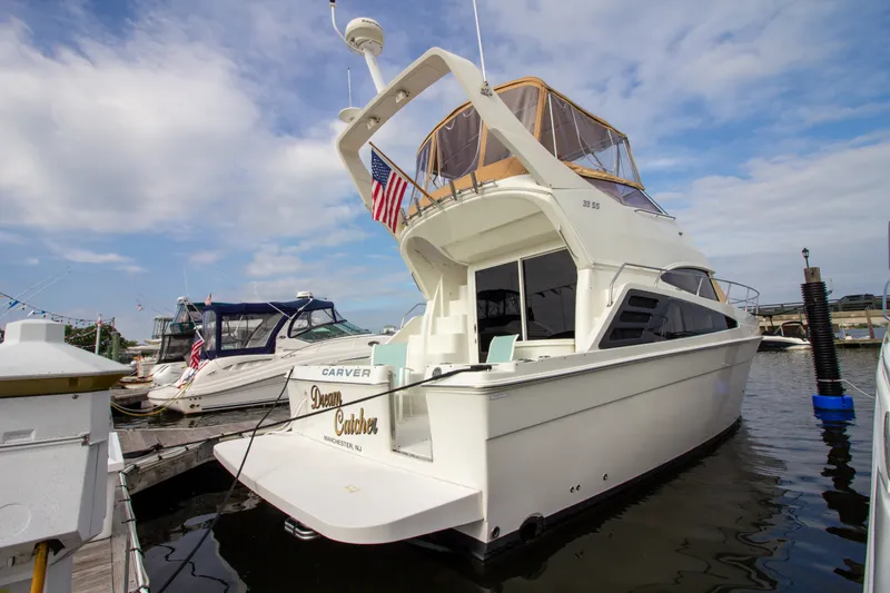 Slide: The Image of A 2006 Carver 33 Super Sport yacht docked in a marina, featuring an elevated helm and an American flag. - 15