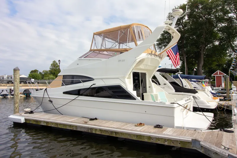 Slide: The Image of A 2006 Carver 33 Super Sport docked. It features an elevated helm and a flag. - 19