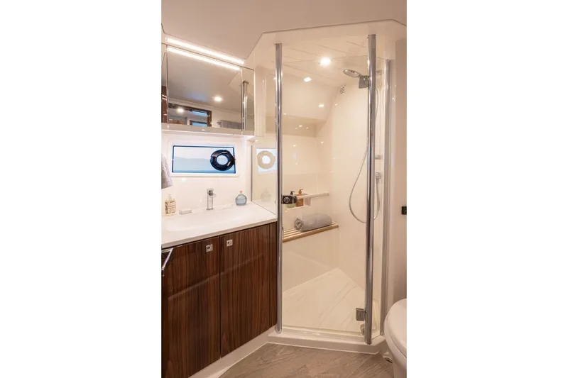 Slide: The Image of Modern bathroom with glass shower, wooden cabinets, and a small window. - 17