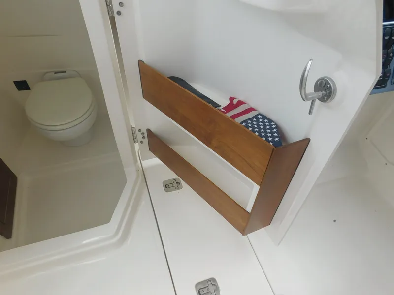 Slide: The Image of The image shows the interior of a boat with a toilet and a door featuring wooden shelves. - 7