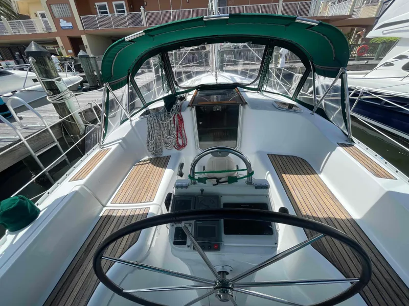 Slide: The Image of Cockpit of 2004 Beneteau 361 sailboat with green canopy and wooden deck accents. - 2