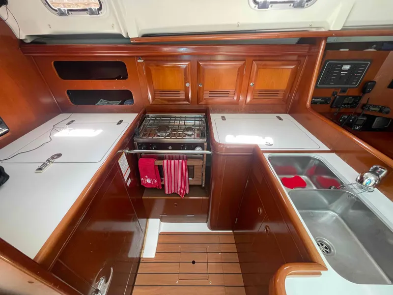 Slide: The Image of 2004 Beneteau 361 yacht kitchen with wood cabinetry, stove, and dual sink. - 5
