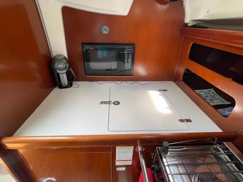 Slide: The Image of 2004 Beneteau 361 yacht galley with microwave, coffee maker, and storage compartments. - 12