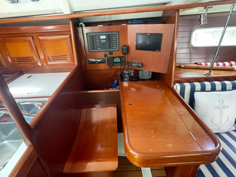 Slide: The Image of Interior of a 2004 Beneteau 361 sailboat with wooden cabinetry and navigation equipment. - 43