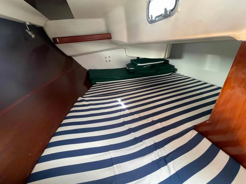 Slide: The Image of Cozy cabin interior of 2004 Beneteau 361 sailboat with striped bedding and wooden accents. - 9