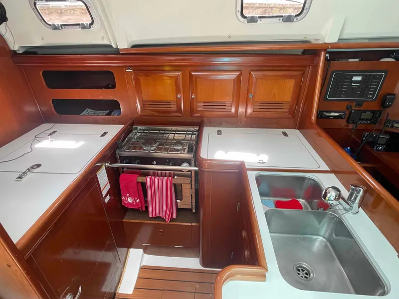 Slide: The Image of 2004 Beneteau 361 yacht kitchen with stove, sink, and wooden cabinetry. - 40