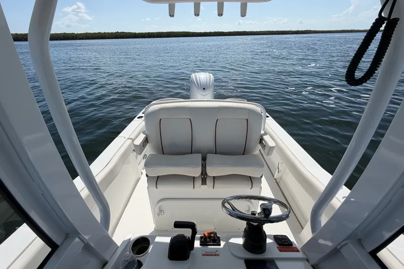 Slide: The Image of 2022 Sea Hunt Ultra 239SE boat interior with helm and seating, overlooking calm waters. - 32