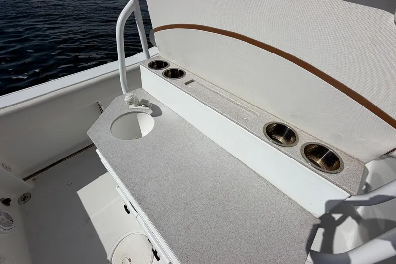 Slide: The Image of 2022 Sea Hunt Ultra 239SE boat interior with cup holders and sink, near water. - 43