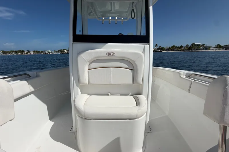 Slide: The Image of 2022 Sea Hunt Ultra 239SE boat interior with white seating, on calm water. - 12