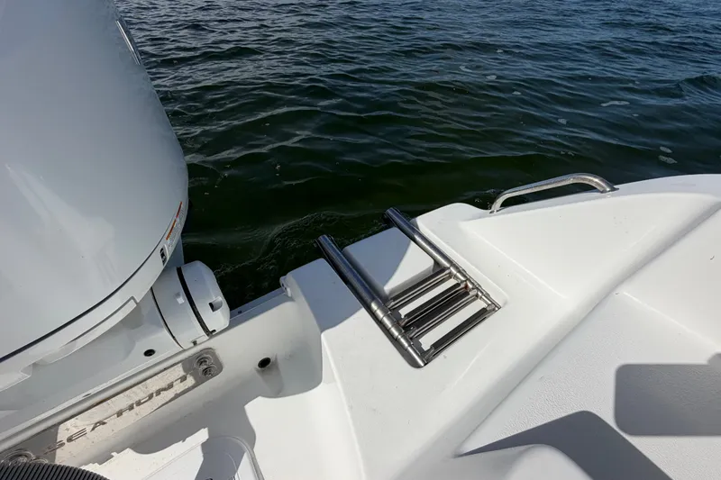 Slide: The Image of 2022 Sea Hunt Ultra 239SE boat with stainless steel swim ladder and outboard motor on water. - 45