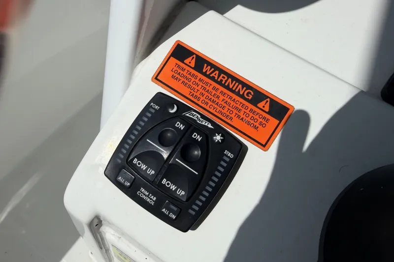 Slide: The Image of Trim tab control panel on 2022 Sea Hunt Ultra 239SE boat with warning label. - 25
