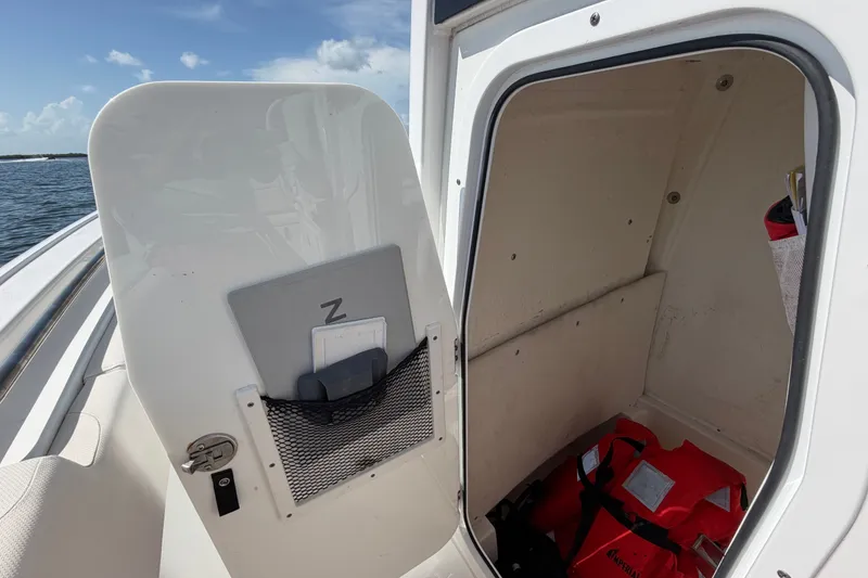 Slide: The Image of 2022 Sea Hunt Ultra 239SE boat storage compartment with life jackets and open door. - 15