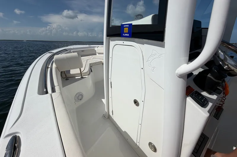 Slide: The Image of 2022 Sea Hunt Ultra 239SE boat interior with seating and console, on calm water. - 13