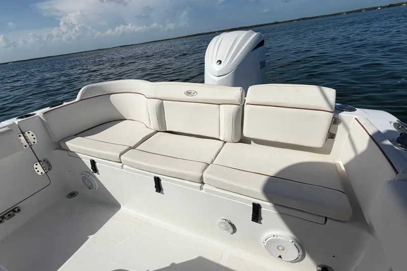 Slide: The Image of 2022 Sea Hunt Ultra 239SE boat with white cushioned seating on calm water. - 36