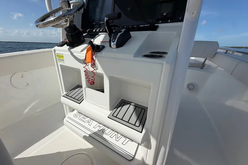 Slide: The Image of 2022 Sea Hunt Ultra 239SE boat console with steering wheel and controls, on open water. - 29