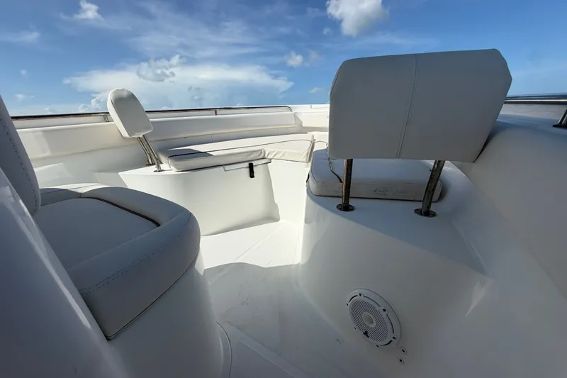Slide: The Image of 2022 Sea Hunt Ultra 239SE boat interior with white seating under a clear blue sky. - 27