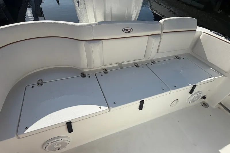 Slide: The Image of 2022 Sea Hunt Ultra 239SE boat seating area with storage compartments and speaker. - 54
