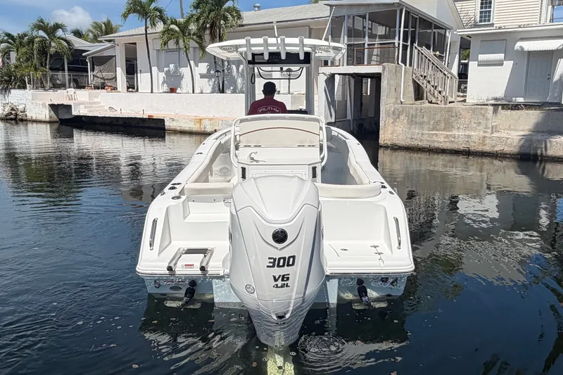 Slide: The Image of 2022 Sea Hunt Ultra 239SE boat docked in a canal with palm trees and houses. - 7