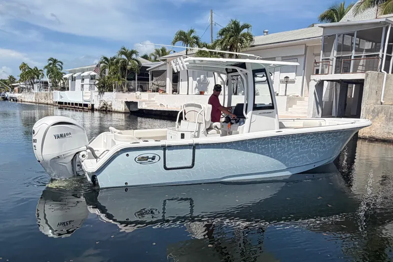 Slide: The Image of 2022 Sea Hunt Ultra 239SE boat on calm water near waterfront homes. - 6