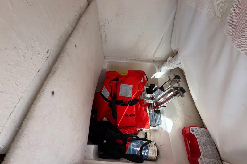 Slide: The Image of Storage compartment in a 2022 Sea Hunt Ultra 239SE with life jackets and safety equipment. - 16