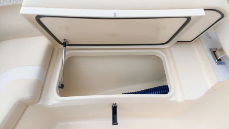 Slide: The Image of An open storage compartment on a Scout 260 LXF boat, with a blue hose inside. - 19