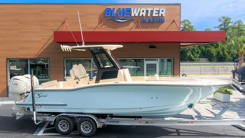 Slide: The Image of A 2027 Scout 260 LXF boat on a trailer in front of a Bluewater Marine building. - 24