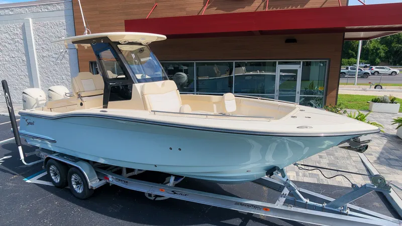 The Image of A 2027 Scout 260 LXF boat on a trailer in front of a modern building. - 1
