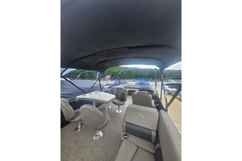 Slide: The Image of 2019 Bennington SX 23 SPDXP pontoon boat interior with seating and table, docked at marina. - 13