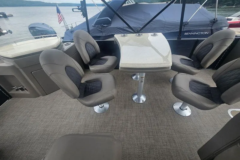 Slide: The Image of 2019 Bennington SX 23 SPDXP boat interior with seating and table on a lake. - 5