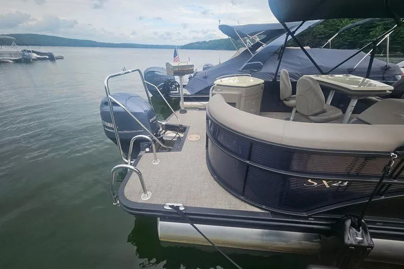 Slide: The Image of 2019 Bennington SX 23 SPDXP pontoon boat docked on a serene lake. - 3